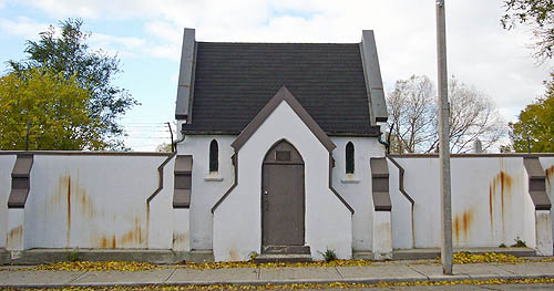 Whitewashed stucco walls are discolored yellow and frame a door inset in a projected vestibule