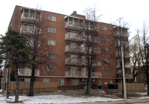 Six-storey brown-brick building has balconies at edges and centre