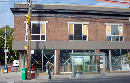 Brick building with plate-glass windows and well-finished slate-grey stucco trip along roofline of ground floor